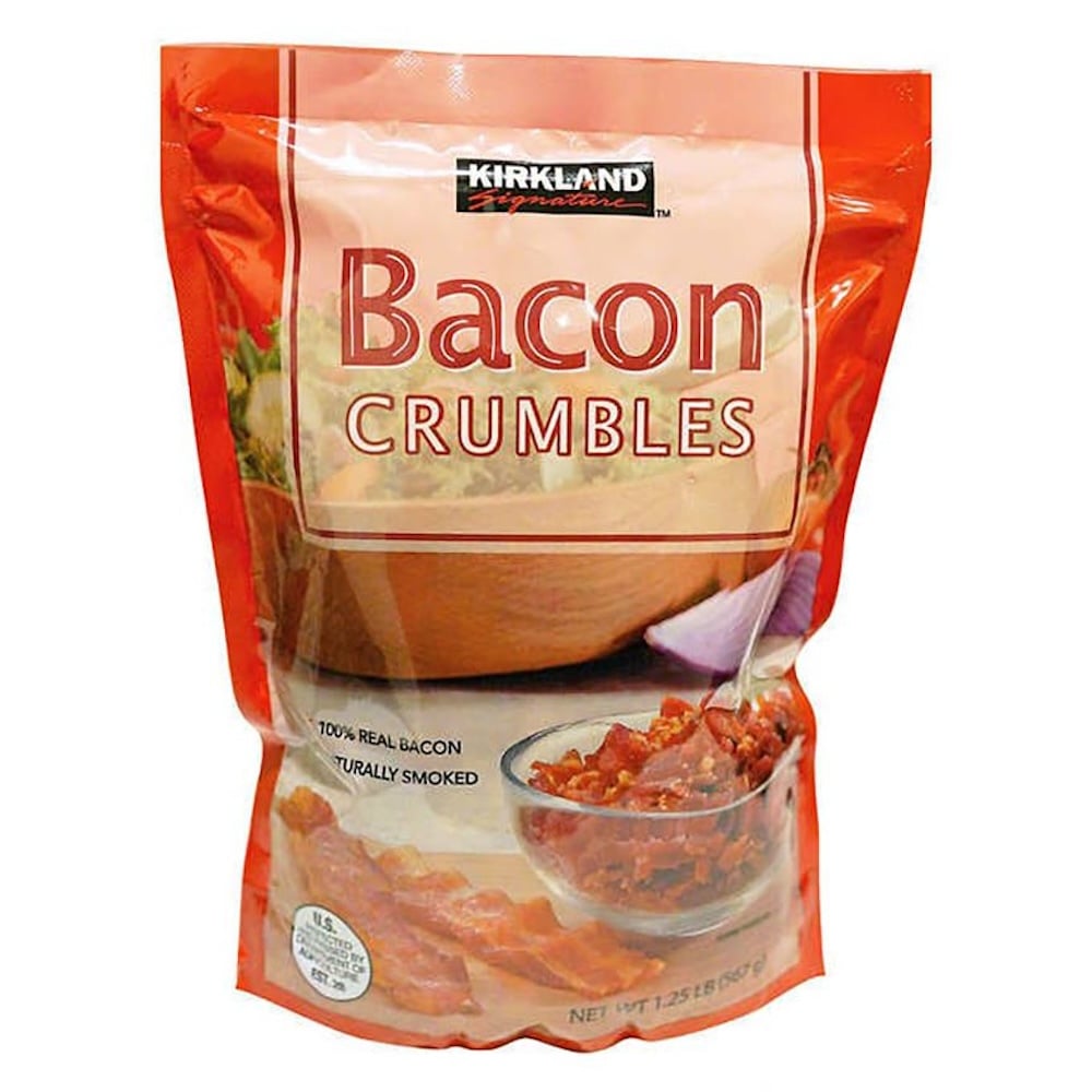 A bag of Kirkland Signature Bacon Crumbles, featuring images of bacon pieces and a salad on the packaging—perfect for your Costco Thanksgiving dishes. The label states "100% real bacon" and "naturally smoked," with a net weight of 1.25 lbs (567 g).