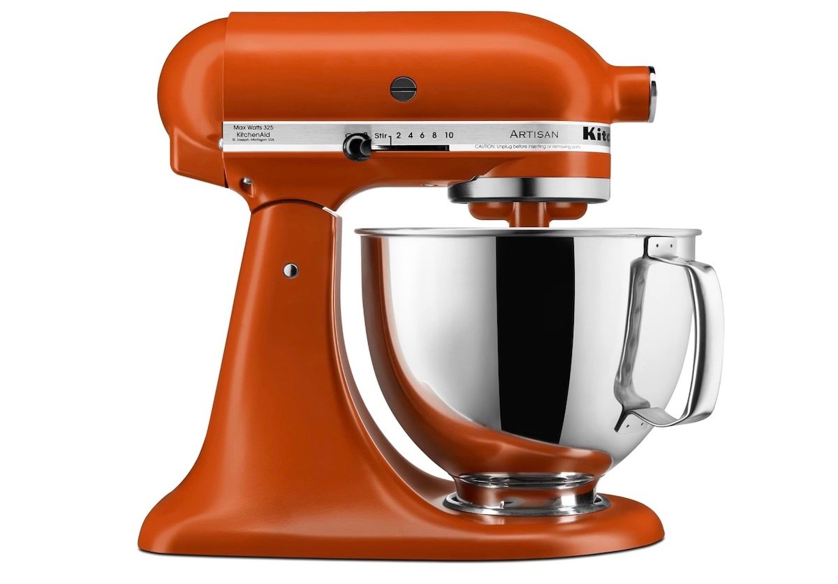 An orange KitchenAid Artisan stand mixer with a stainless steel mixing bowl, shown in profile view against a white background.