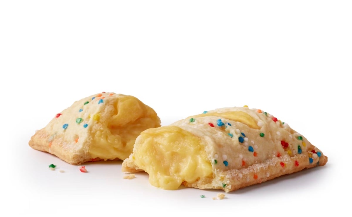 Two rectangular pastries with a golden, flaky crust topped with colorful sprinkles, one cut open to reveal a creamy yellow filling, set on a white background.
