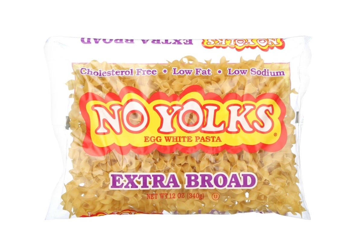 A clear plastic package of No Yolks Extra Broad Egg White Pasta, labeled as cholesterol free, low fat, and low sodium, with yellow and red branding.