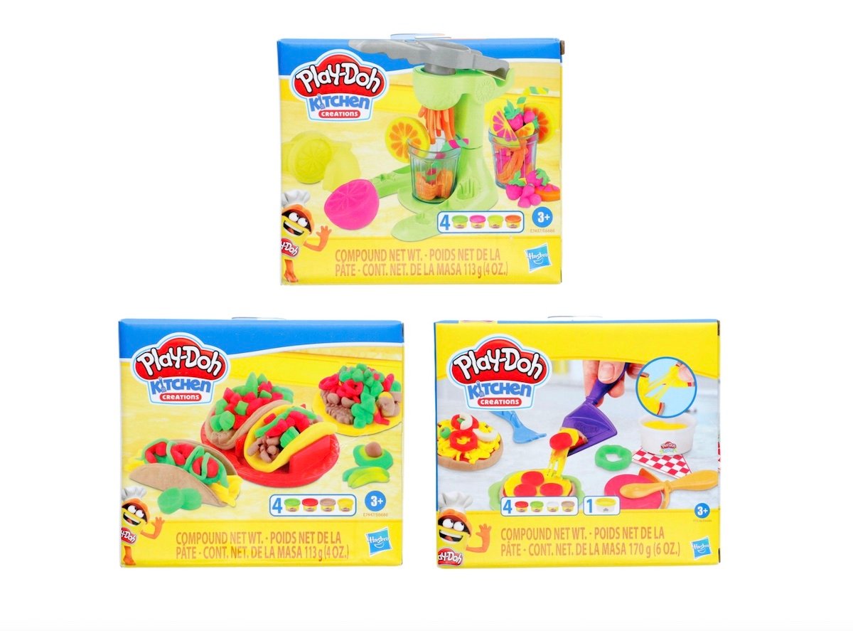 Three Play-Doh Kitchen Creations sets in colorful boxes are shown, featuring play food designs for tacos, a pizza, and a smoothie maker. Each box displays the Play-Doh logo and age recommendations for children 3 and up.