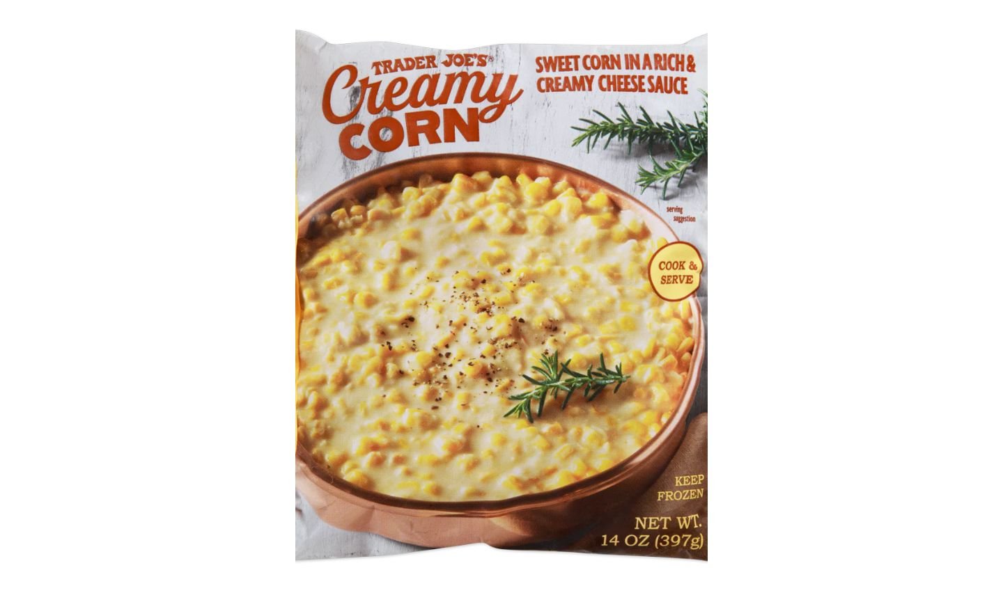 A package of Trader Joe's Creamy Corn, featuring an image of corn in a rich cheese sauce garnished with herbs. The package states "Sweet Corn in a Rich & Creamy Cheese Sauce" and weighs 14 oz (397g).
