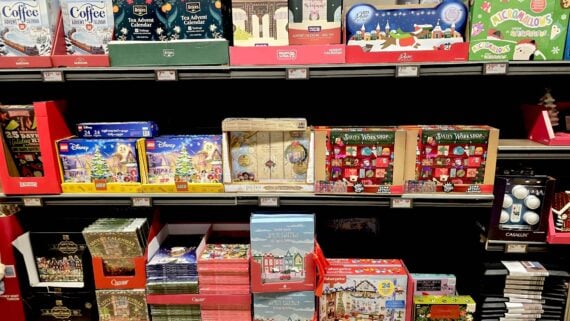 Shelves filled with various advent calendars and Christmas-themed gift sets, including Disney, tea, coffee, and beauty products, all neatly arranged in colorful packaging.