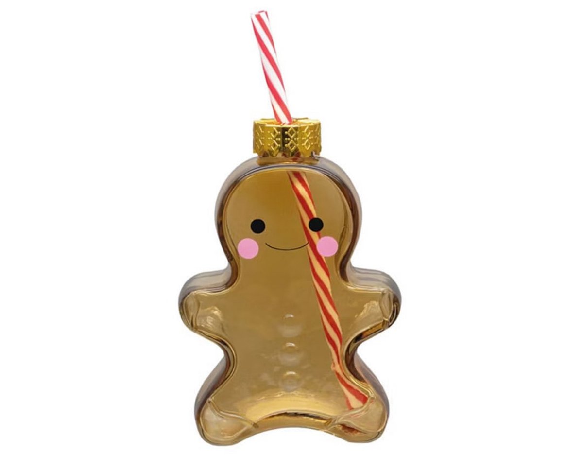 A gingerbread man-shaped clear bottle with a gold cap, decorated with a smiling face and pink cheeks, and a red-and-white striped straw inserted through the top.