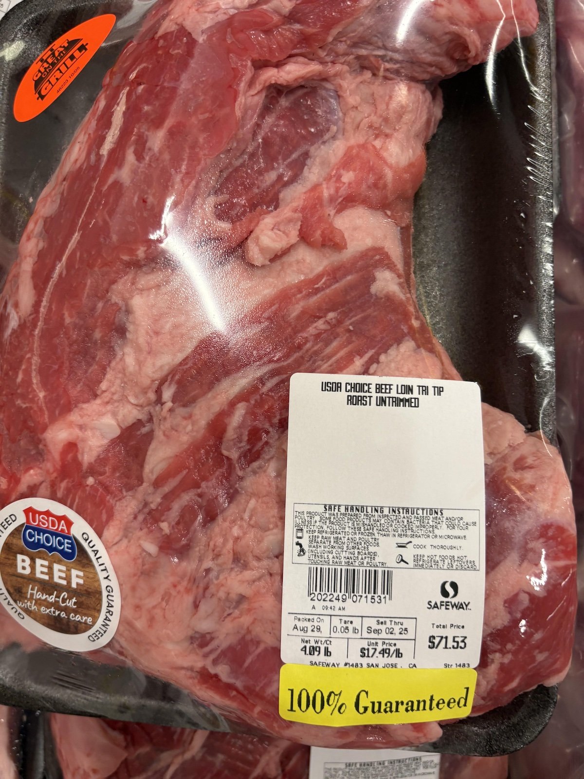 A packaged USDA Choice beef loin tri tip roast sits on display. The price tag shows it weighs 4.21 lbs at $17.99 per pound, totaling $71.53, and features a yellow "100% Guaranteed" label at the bottom.