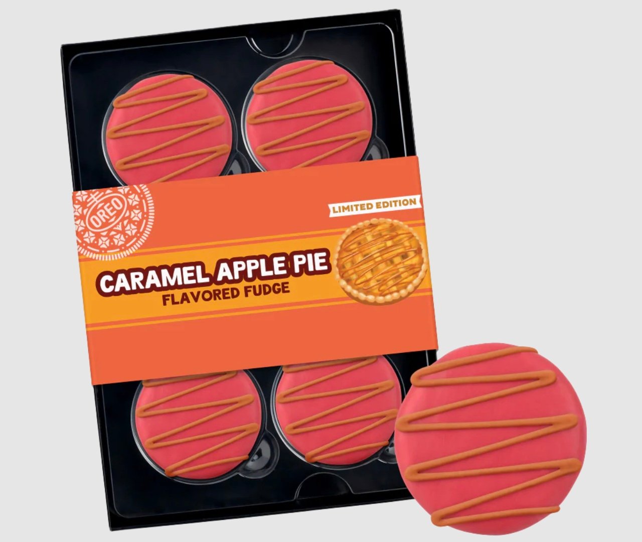 A box of four round, pink fudge treats with caramel drizzle, labeled "Caramel Apple Pie Flavored Fudge—Limited Edition." One treat is shown outside the box for detail.