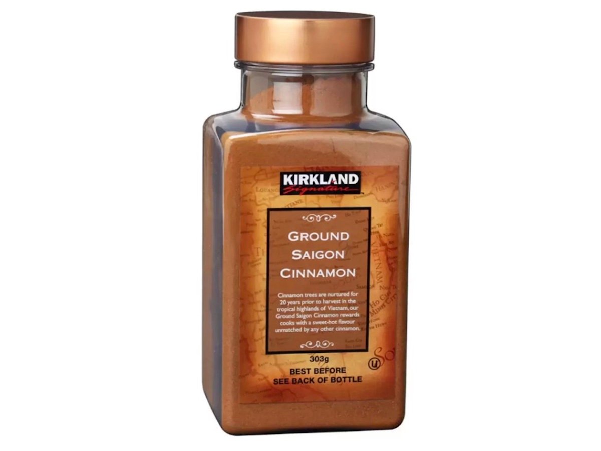 A clear plastic container of Kirkland Signature Ground Saigon Cinnamon with a brown label, showing product details and weighing 303 grams.