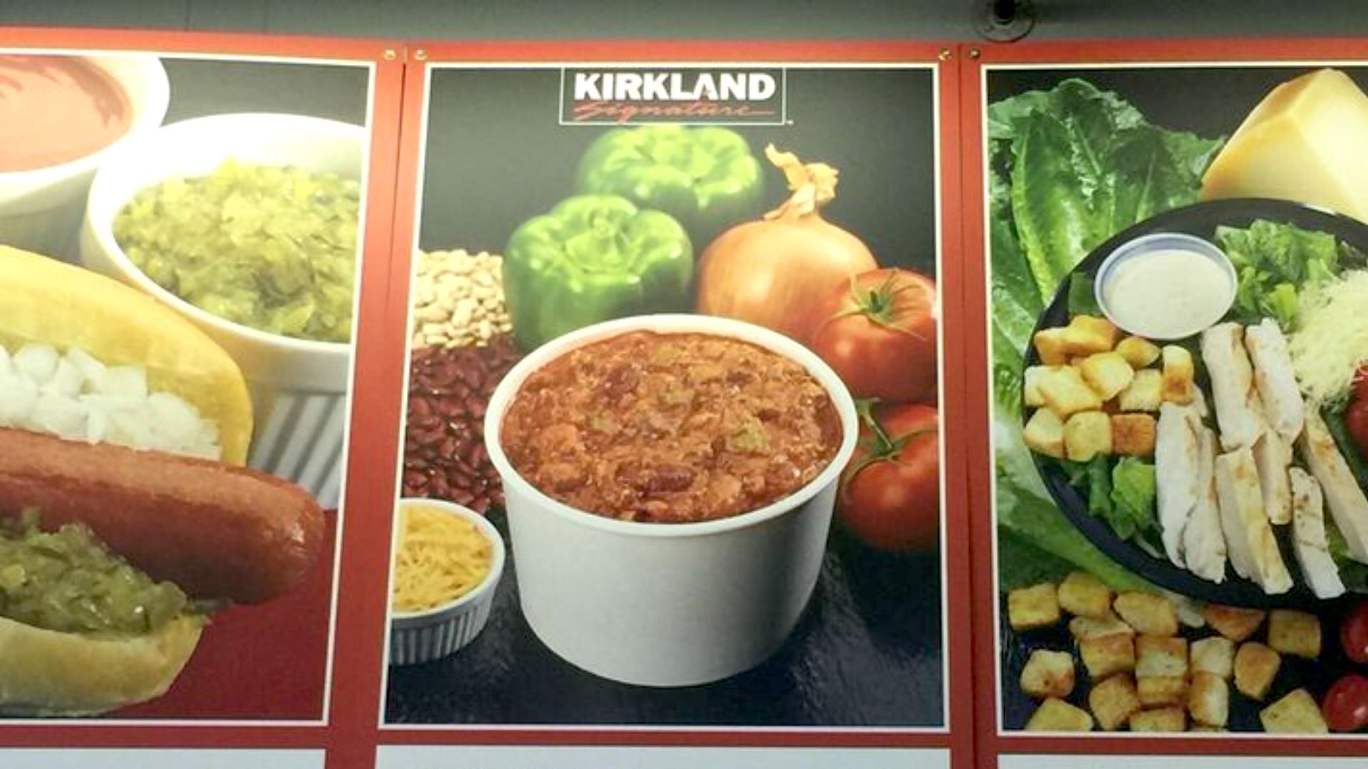 A poster displays a cup of chili surrounded by green bell peppers, an onion, beans, and shredded cheese, with "Kirkland Signature" branding above.