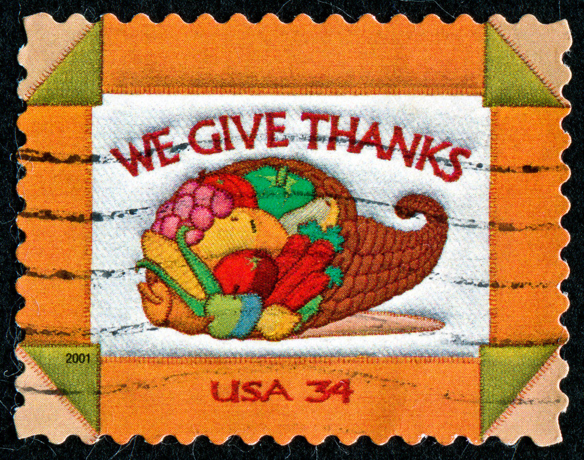 A colorful postage stamp shows a cornucopia filled with fruits and vegetables, symbolizing gratitude and echoing the spirit of Thanksgiving Dinner Cost History, with "WE GIVE THANKS" above and "USA 34" below on an orange and white background.