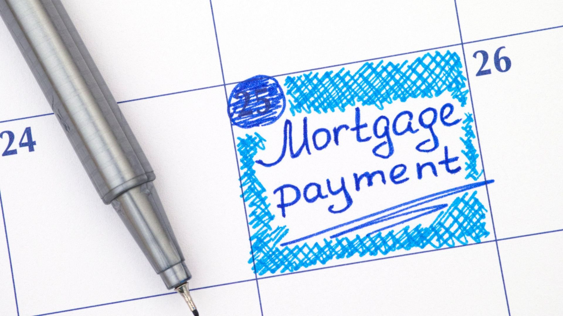 A calendar close-up with a pen resting on it. The 25th is marked with a blue box and labeled "Mortgage payment" in handwritten text, highlighting an important financial reminder.