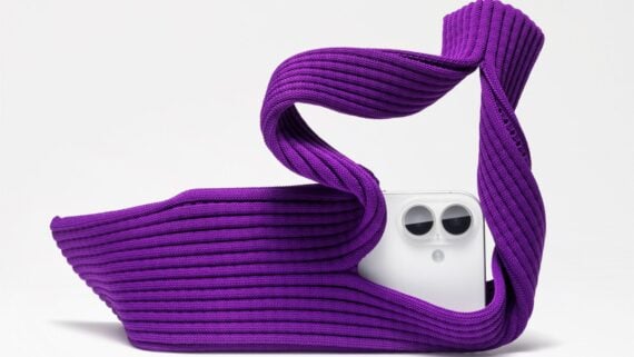 A white smartphone with dual cameras is partially wrapped in a twisted, ribbed purple fabric against a plain white background.