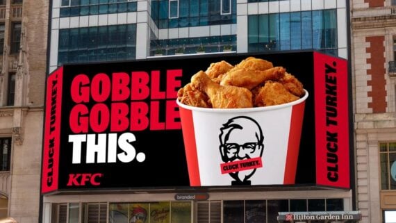 A large KFC billboard displays a bucket of fried chicken with the words "GOBBLE GOBBLE THIS." in bold text. The Colonel Sanders logo has "CLUCK TURKEY" over his mouth, and "CLUCK TURKEY" is repeated on the edges.