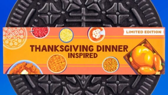 A close-up of an Oreo cookie package labeled "Thanksgiving Dinner Inspired" with images of turkey, pumpkin pie, cranberry sauce, corn, mashed potatoes, and green beans on an orange background.