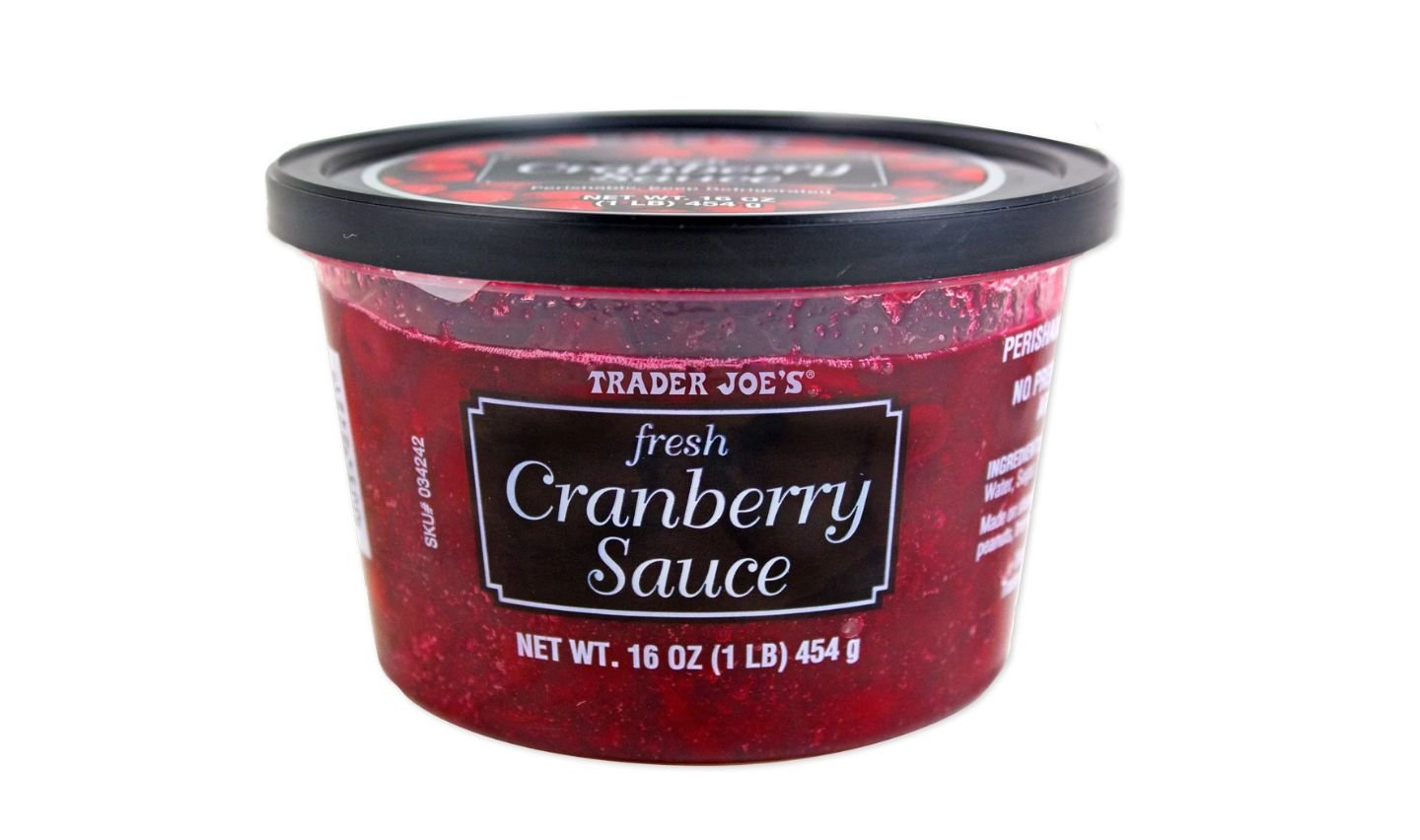 A 16-ounce container of Trader Joe's fresh cranberry sauce with a black lid and a clear tub showing the red sauce inside. The label on the front displays the product name and weight.