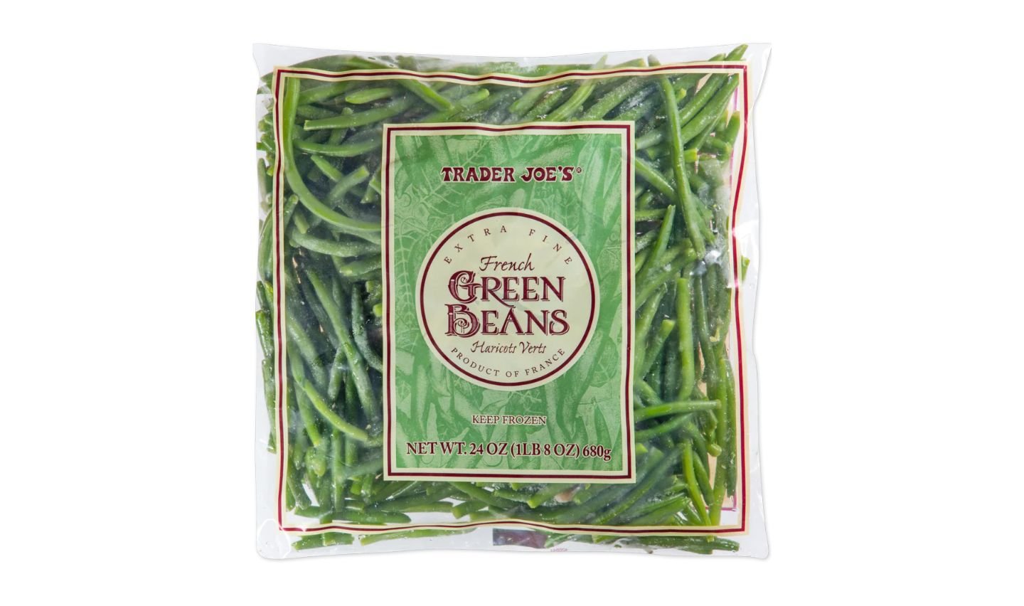 A clear bag of Trader Joe's Extra Fine French Green Beans, showing the green beans inside. The label indicates a net weight of 24 oz (1.5 lbs) and that the beans are a product of France and are frozen.