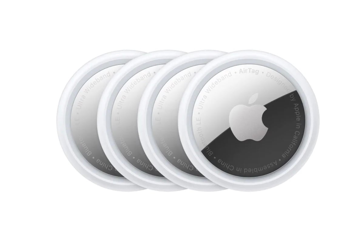 Four Apple AirTags are stacked in a row, each with a white outer rim and a silver center displaying the Apple logo.