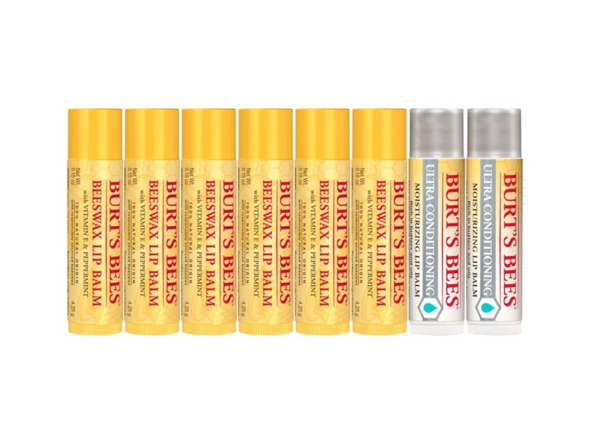 Eight tubes of Burt's Bees lip balm are lined up, with six yellow tubes labeled "Beeswax Lip Balm" and two silver tubes labeled "Ultra Conditioning" on a white background.
