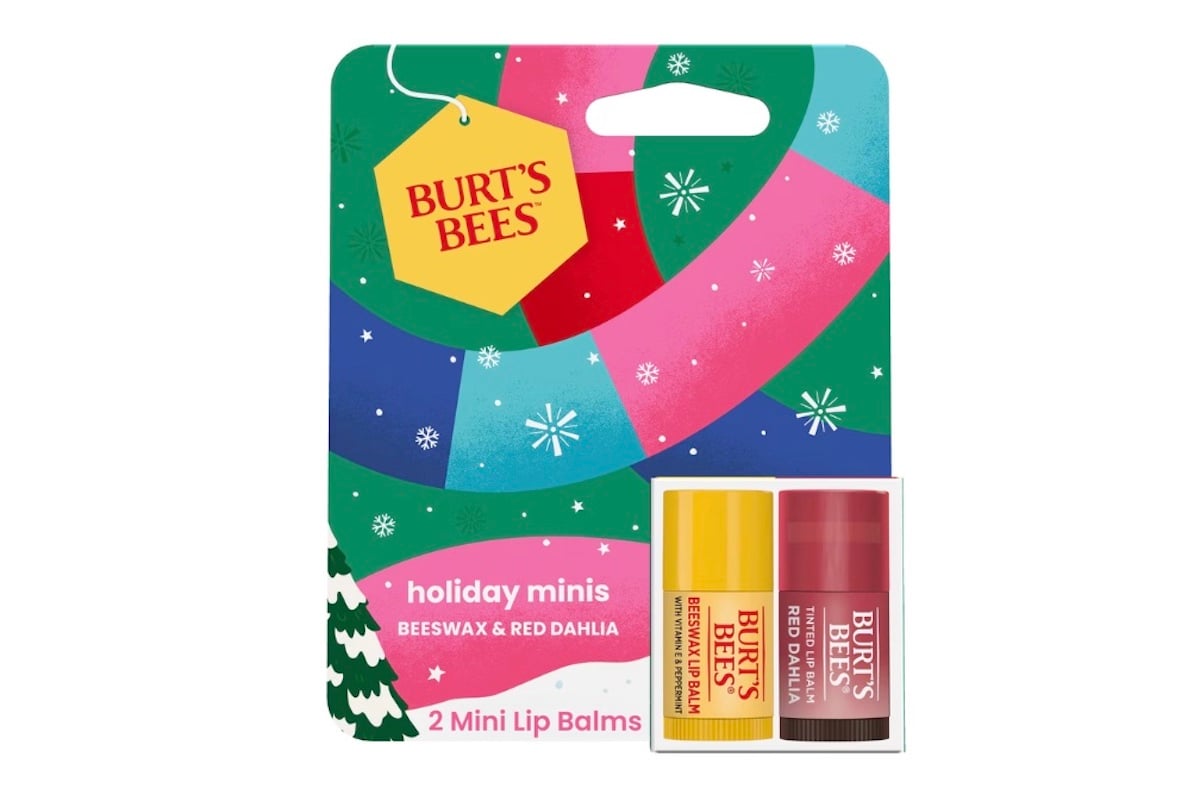 A package of Burt’s Bees holiday minis featuring two mini lip balms—one in yellow (beeswax) and one in red (red dahlia)—against a festive, colorful background with snowflakes.