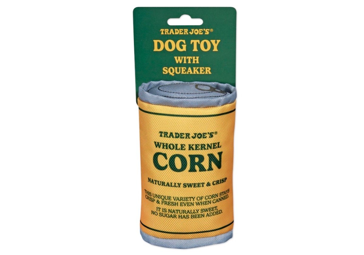A dog toy shaped like a can of Trader Joe’s whole kernel corn, with a green and yellow label and text that reads “Dog Toy with Squeaker” and “Naturally Sweet & Crisp.”