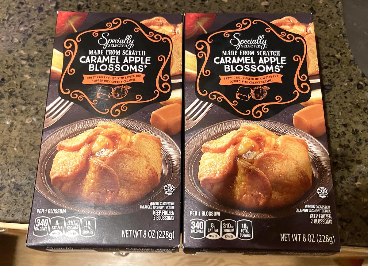 Two boxes of Specially Selected Caramel Apple Blossoms are on a granite countertop. Each box displays an image of the dessert, which is a pastry filled with caramel and apple, and lists nutritional information.