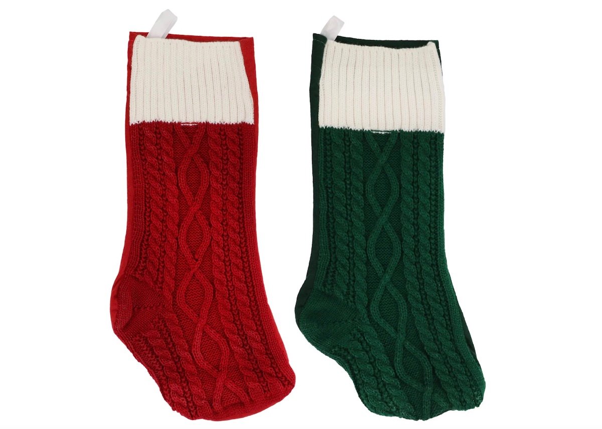 Two knitted Christmas stockings, one red with a white cuff and one green with a white cuff, both featuring a cable knit pattern, are displayed side by side on a white background.
