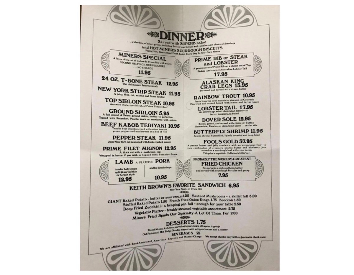 A vintage dinner menu featuring steak, seafood, chicken, lamb, and pork dishes with prices. Includes options like T-bone steak, prime rib, lobster tail, fried chicken, sandwiches, and desserts. Black text on white background.