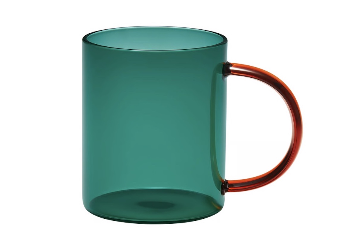 A translucent green glass mug with a contrasting orange handle, set against a white background.