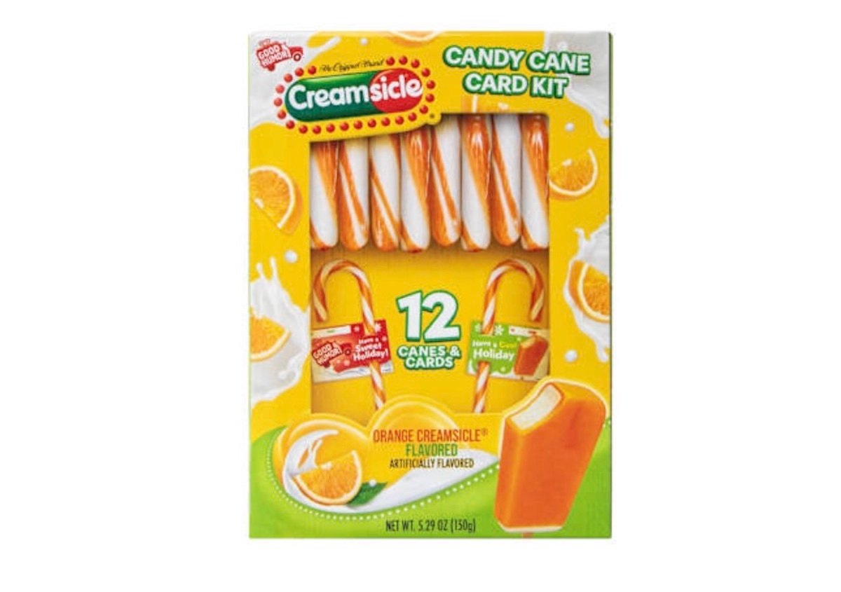 A box of Creamsicle Candy Cane Card Kit featuring 12 orange and white striped candy canes and holiday cards. The packaging is yellow with orange slices and an image of an orange creamsicle bar.