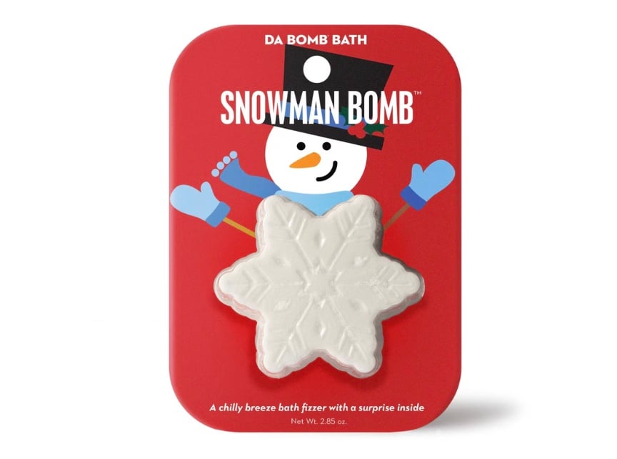 A white snowflake-shaped bath bomb is attached to red packaging featuring a cartoon snowman with a top hat, scarf, and mittens. The text reads "Snowman Bomb" and "A chilly breeze bath fizzer with a surprise inside.