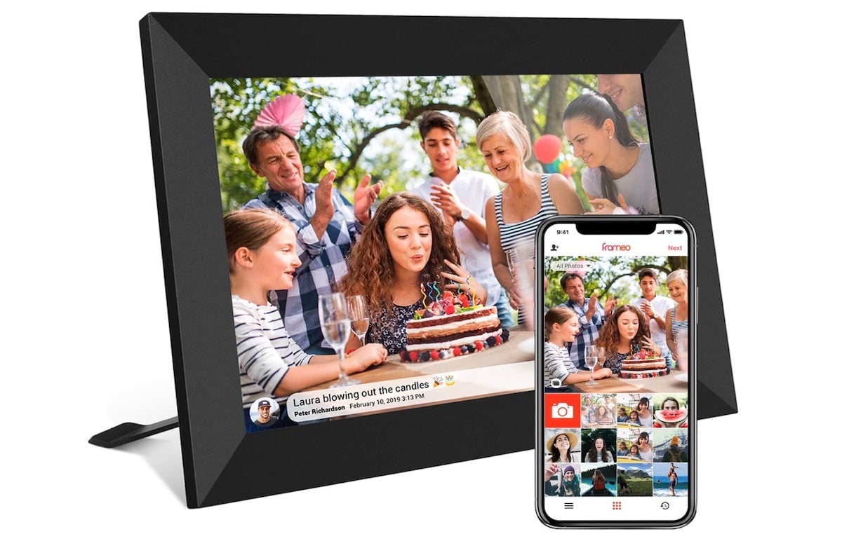 A digital photo frame displays a birthday scene where a young woman blows out candles on a cake, surrounded by smiling people. A smartphone in front shows the same photo and a gallery app.