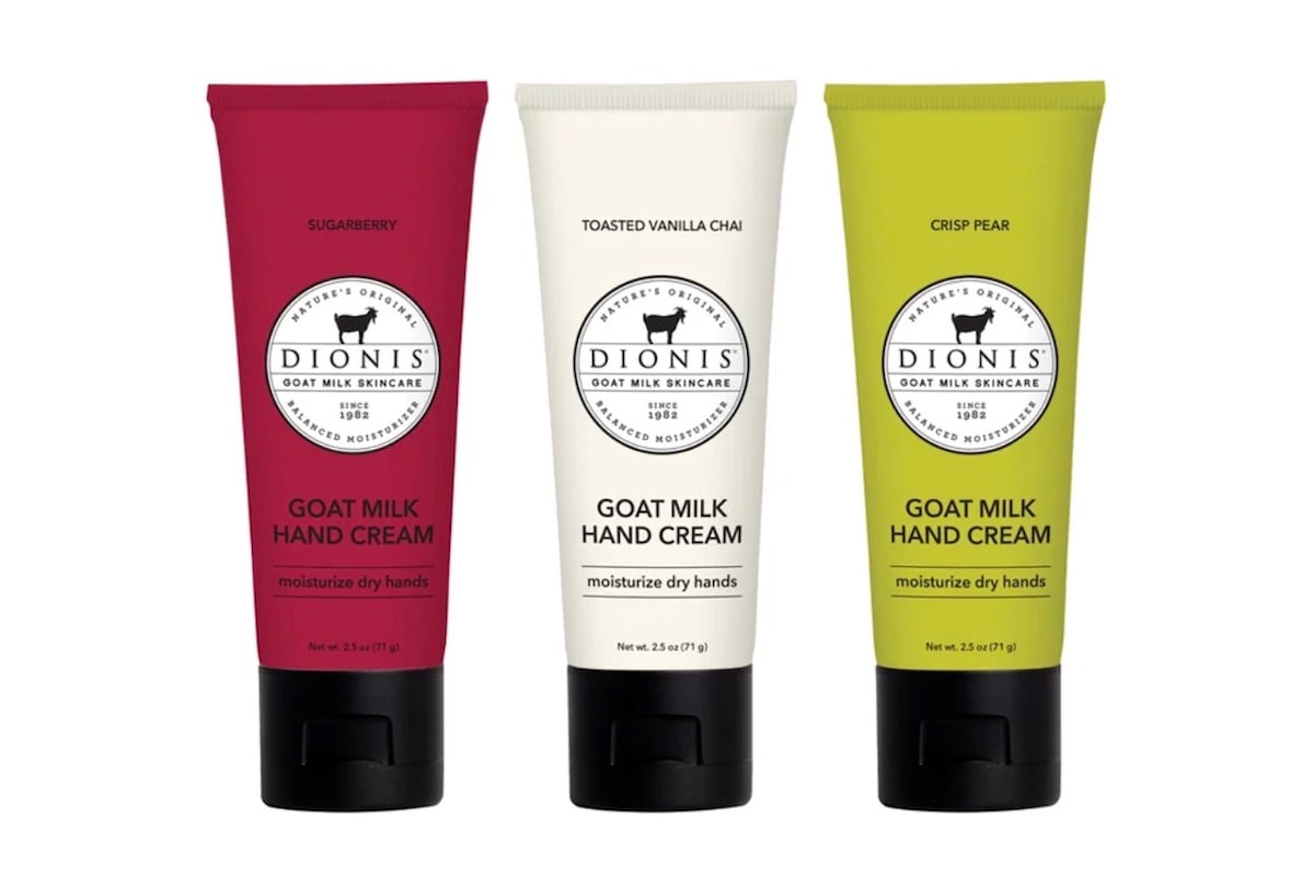 Three tubes of Dionis Goat Milk Hand Cream in different scents: Sugarberry (red tube), Toasted Vanilla Chai (cream tube), and Crisp Pear (green tube), each labeled to moisturize dry hands.