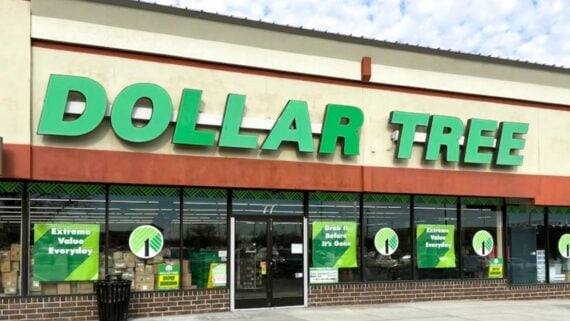 A Dollar Tree store with large green signage on the front and promotional posters in the windows. The entrance features glass doors and a brick sidewalk.