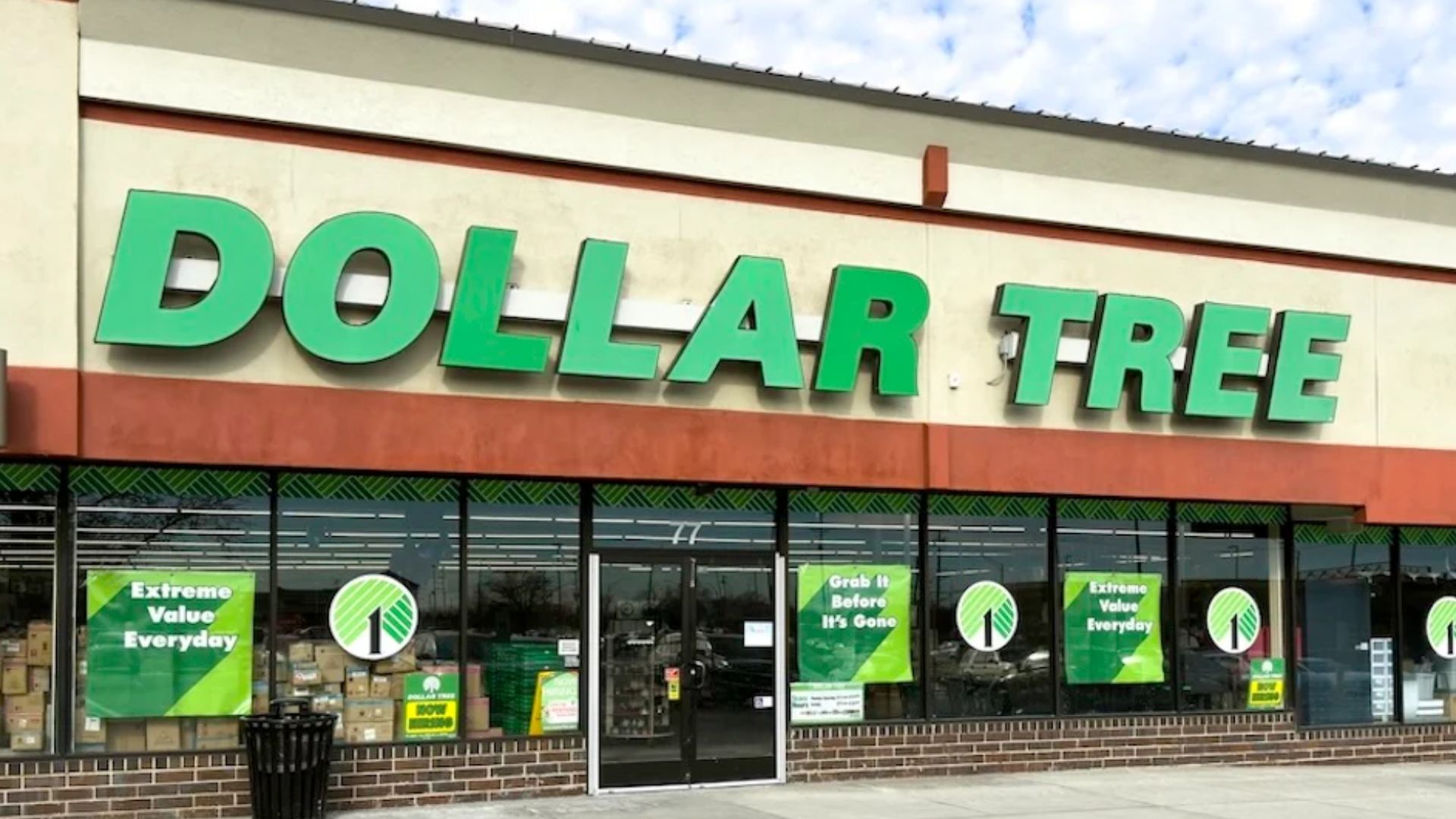 A Dollar Tree store with large green signage on the front and promotional posters in the windows. The entrance features glass doors and a brick sidewalk.