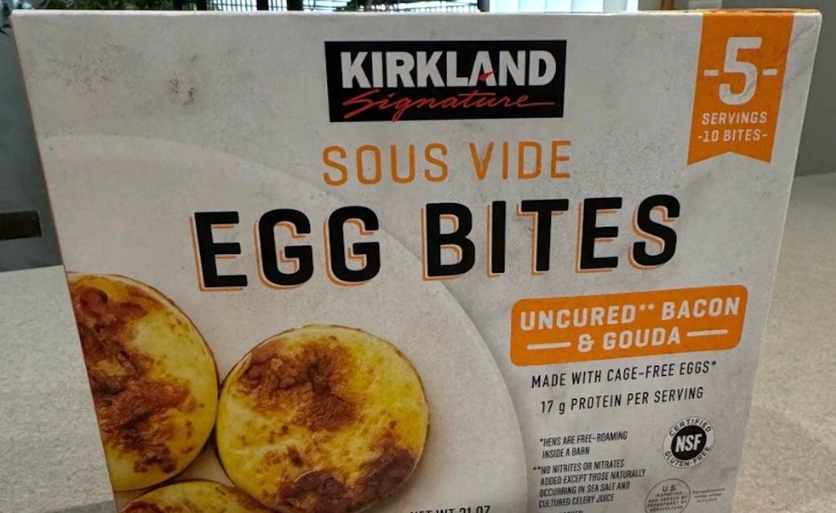 A box of Kirkland Signature Sous Vide Egg Bites, uncured bacon and gouda flavor. The packaging highlights 5 servings, 17g protein per serving, and features an image of the egg bites.