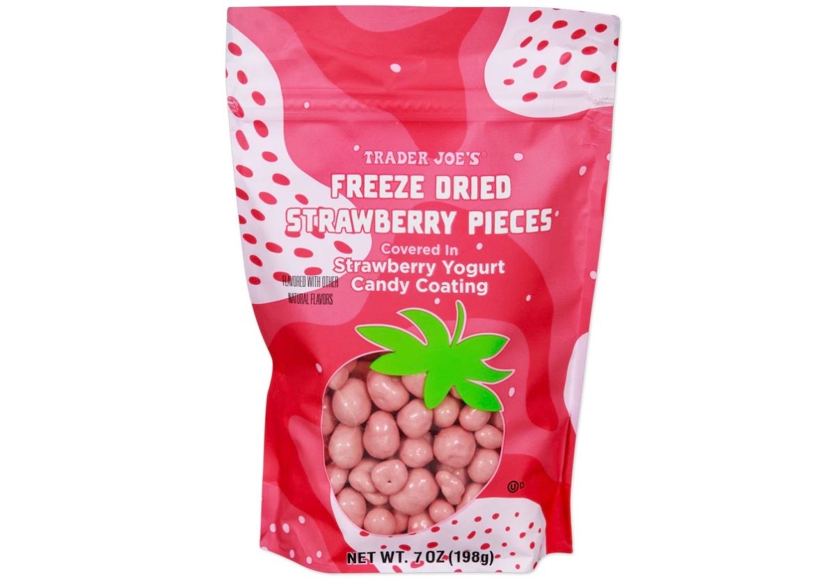 A pink bag of Trader Joe’s Freeze Dried Strawberry Pieces covered in strawberry yogurt candy coating, with strawberry graphics and a clear window showing the round, pink candy inside. Net weight is 7 oz (198g).