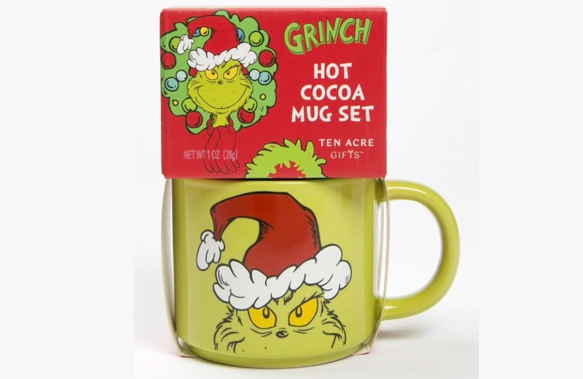 A green mug featuring the Grinch wearing a Santa hat, packaged with a red box labeled “Grinch Hot Cocoa Mug Set” and showing a similar Grinch illustration on the front.