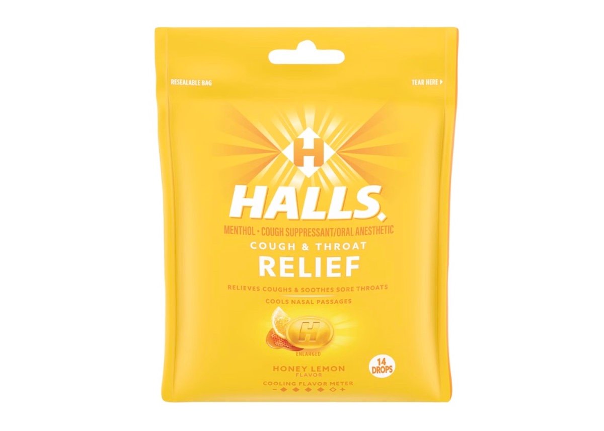 A yellow resealable bag of Halls cough and throat relief drops in honey lemon flavor, containing 14 drops. The packaging highlights menthol, soothing sore throats, and cooling nasal passages.