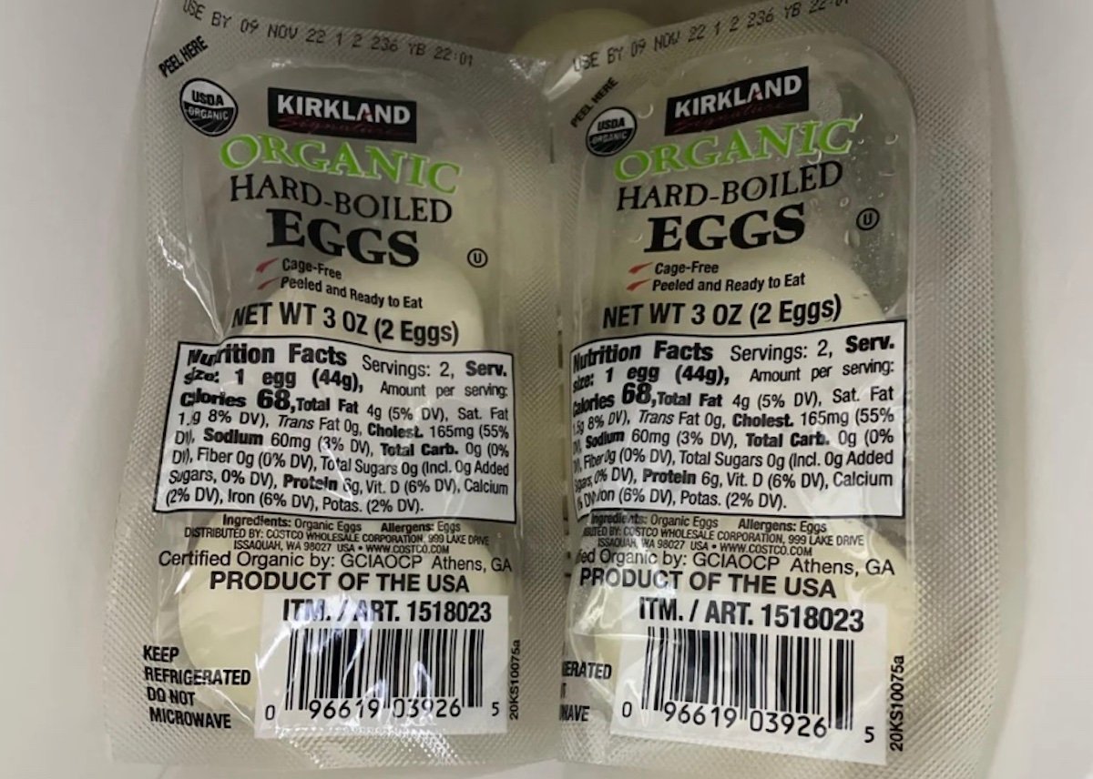Two plastic packs of Kirkland Organic Hard-Boiled Eggs, each containing two peeled eggs with visible nutrition facts labels, are placed side by side in a refrigerator.
