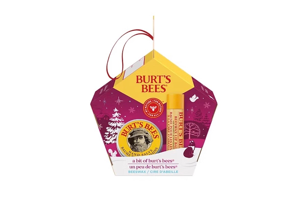 A Burt’s Bees holiday gift set featuring beeswax lip balm and hand salve in a festive, house-shaped package with red, purple, and yellow colors, decorated with white trees and snowflakes.