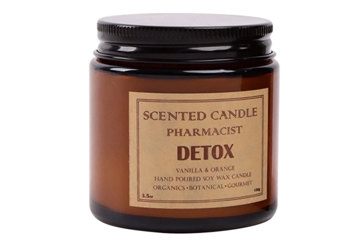 A brown glass jar with a black lid labeled "Scented Candle Pharmacist Detox, Vanilla & Orange, Hand Poured Soy Wax Candle, Organics, Botanical, Gourmet.