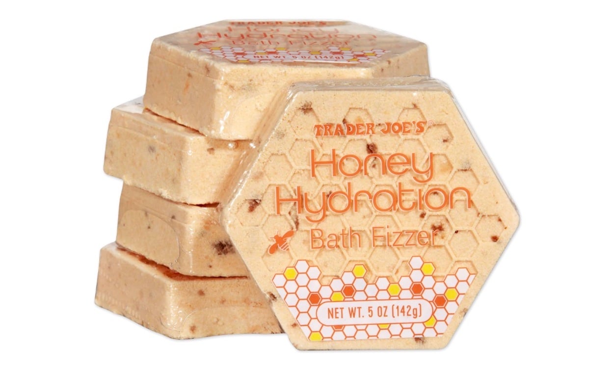 A stack of hexagon-shaped Trader Joe’s Honey Hydration Bath Fizzers, with honeycomb designs and orange text on the packaging, shown against a white background.