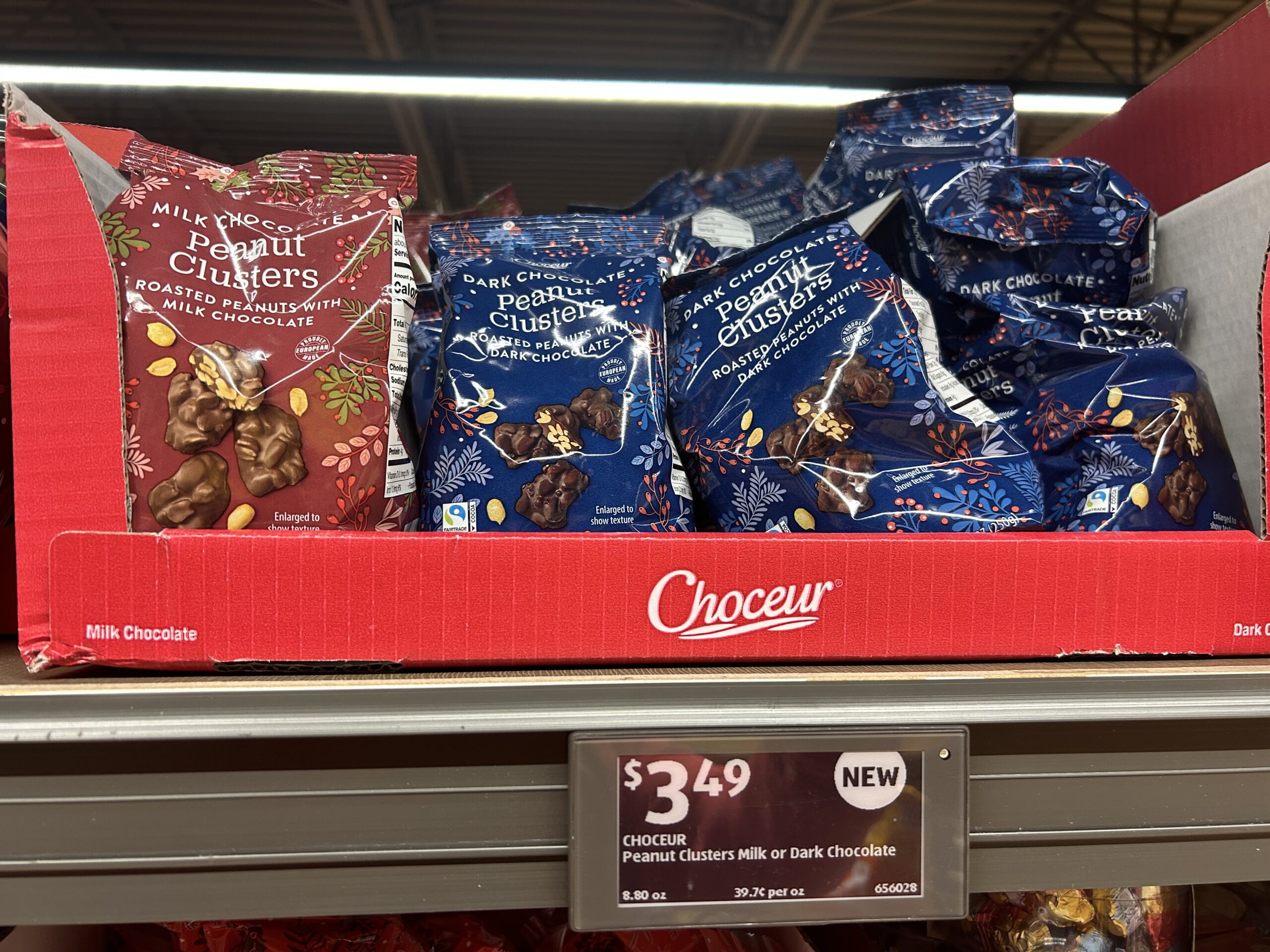 Bags of Choceur Peanut Clusters in milk and dark chocolate varieties are displayed on a store shelf in a red box, priced at $3.49 each.