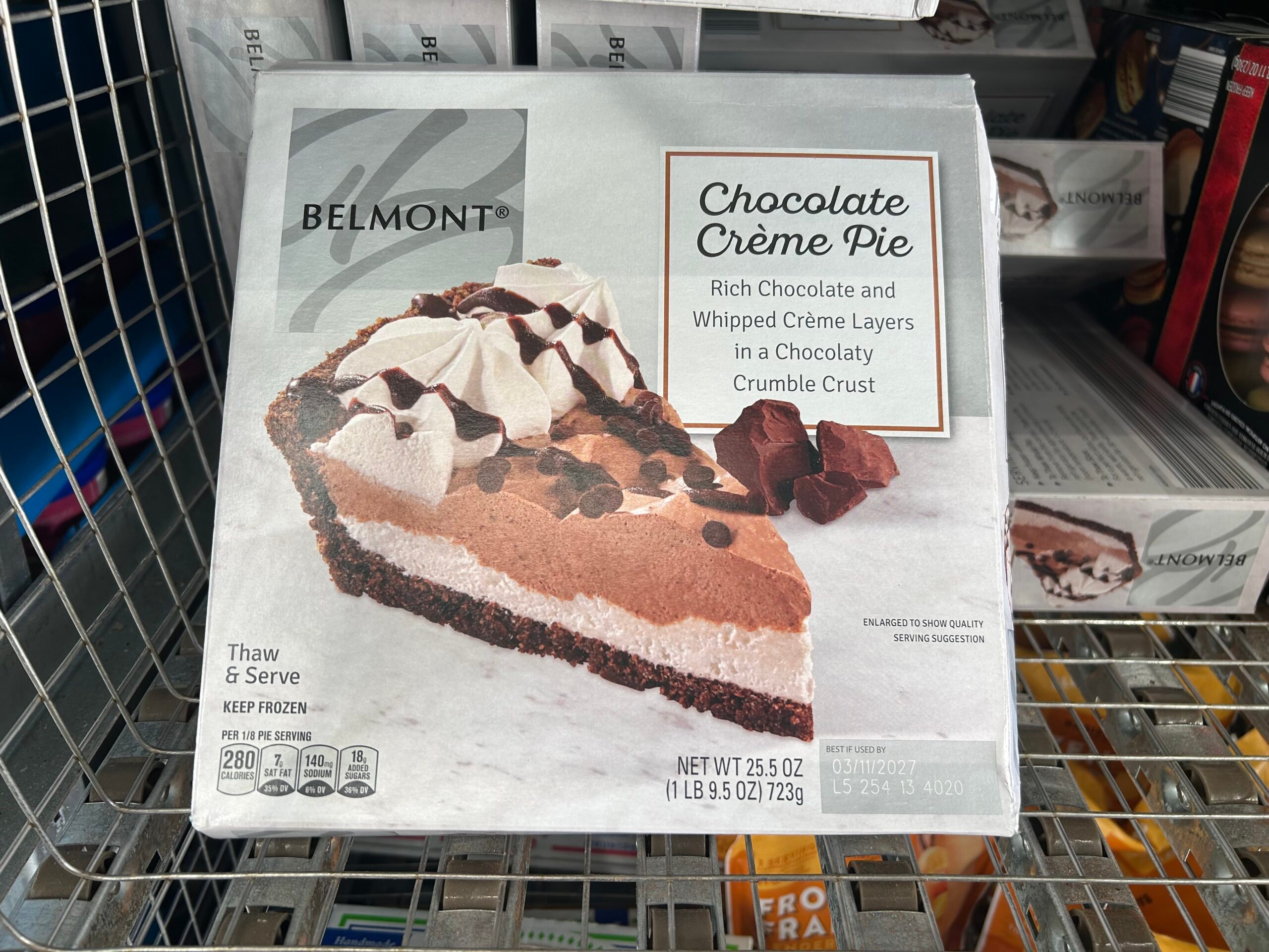 A box of Belmont Chocolate Crème Pie, featuring an image of a chocolate and whipped crème pie with a chocolatey crumble crust. The box is displayed on a store freezer shelf.