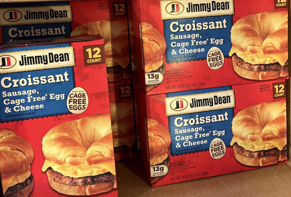 Boxes of Jimmy Dean Croissant Sandwiches featuring sausage, cage-free egg, and cheese are displayed. The packaging highlights "12 count" and "cage free eggs" in bold letters.