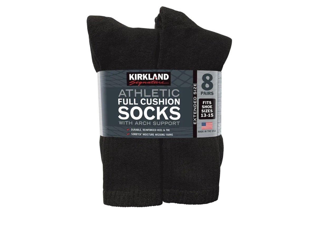 A package of Kirkland Signature Athletic Full Cushion Socks, containing 8 pairs. The socks are black, offer arch support, and fit shoe sizes 13–15. The label highlights durability, moisture wicking, and extended size.