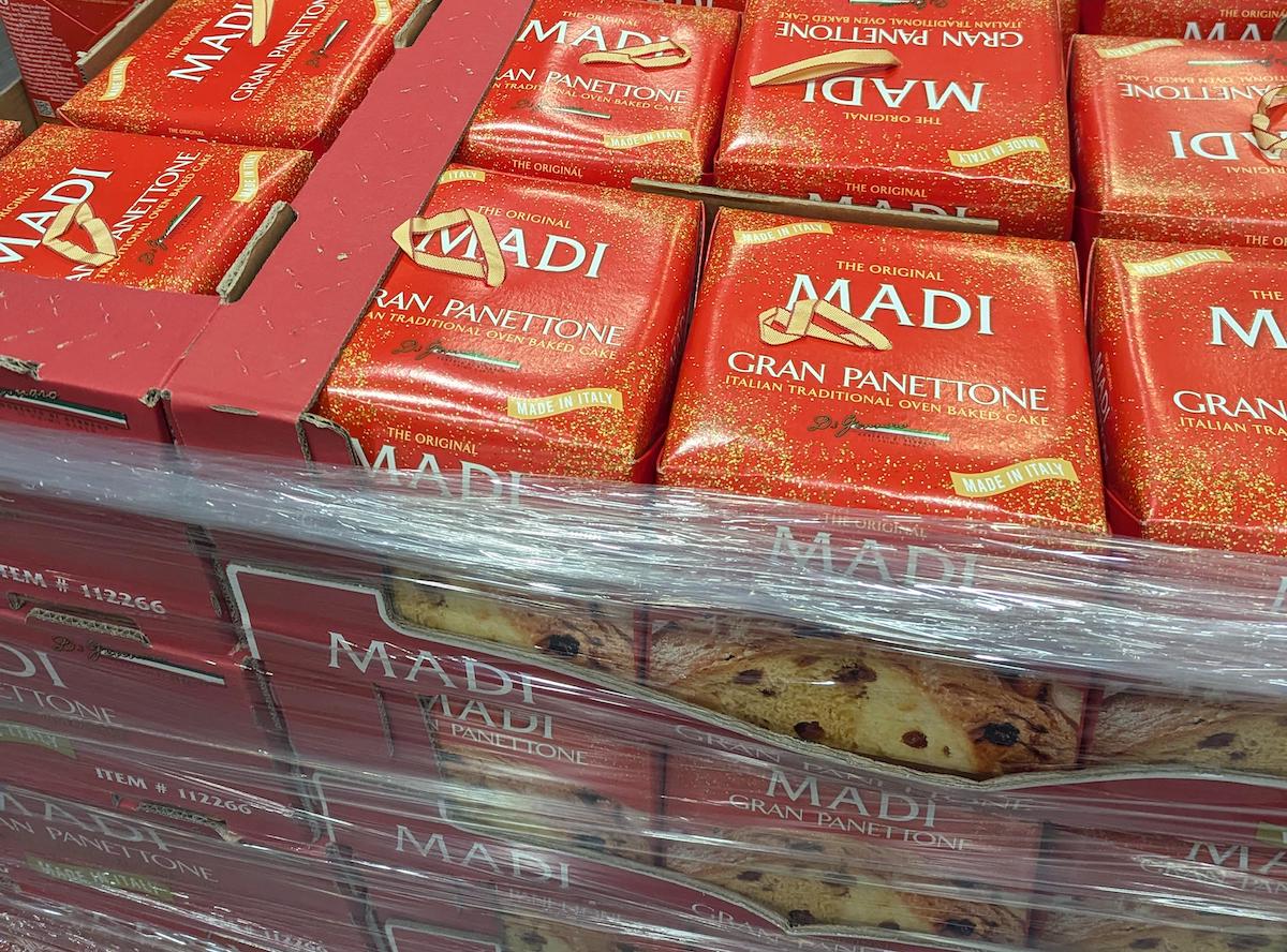 Stacks of red boxes labeled "Madi Gran Panettone" are wrapped in clear plastic on a pallet. The packaging features gold accents and an image of the Italian sweet bread.