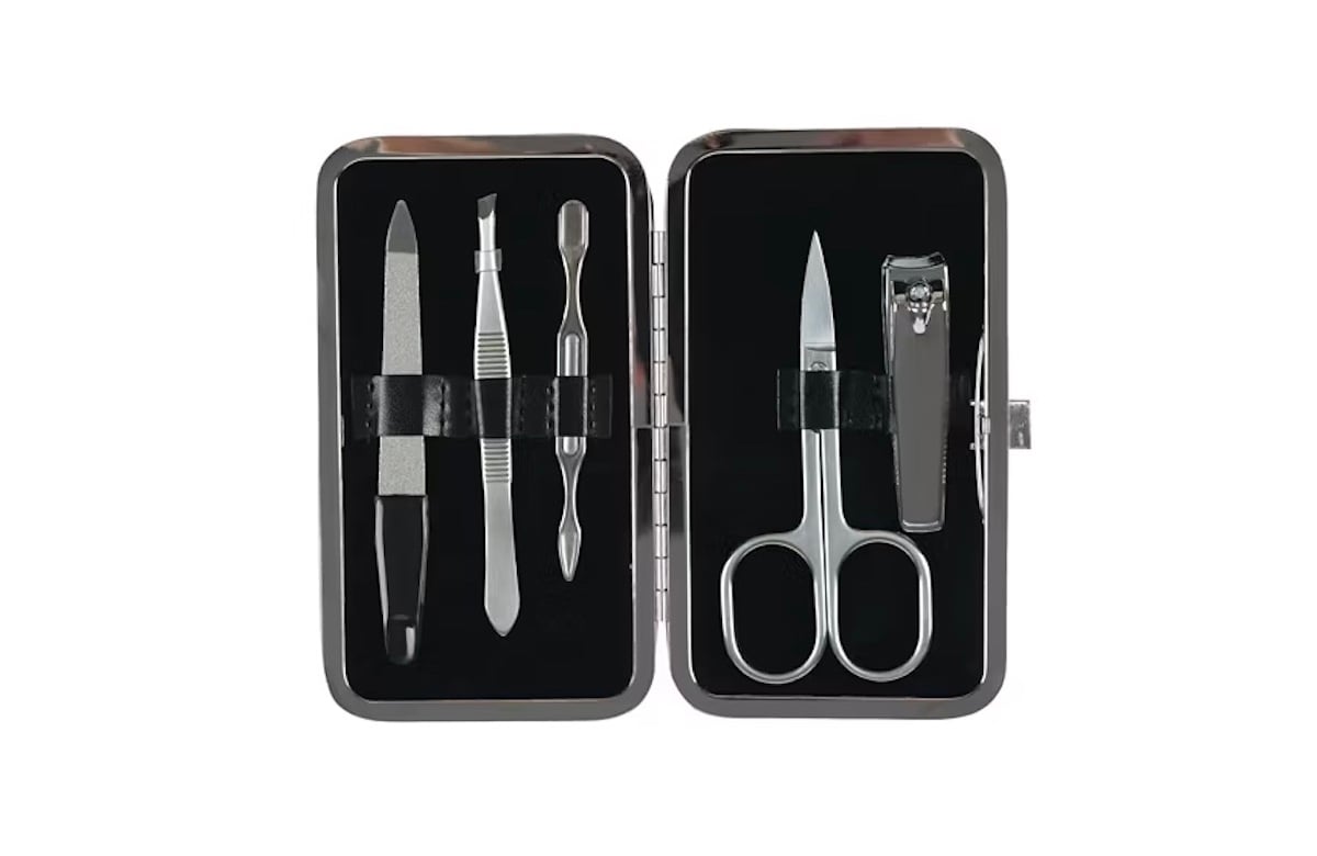 A manicure set in an open black case containing a nail file, cuticle pusher, tweezers, scissors, and nail clippers, all made of metal.