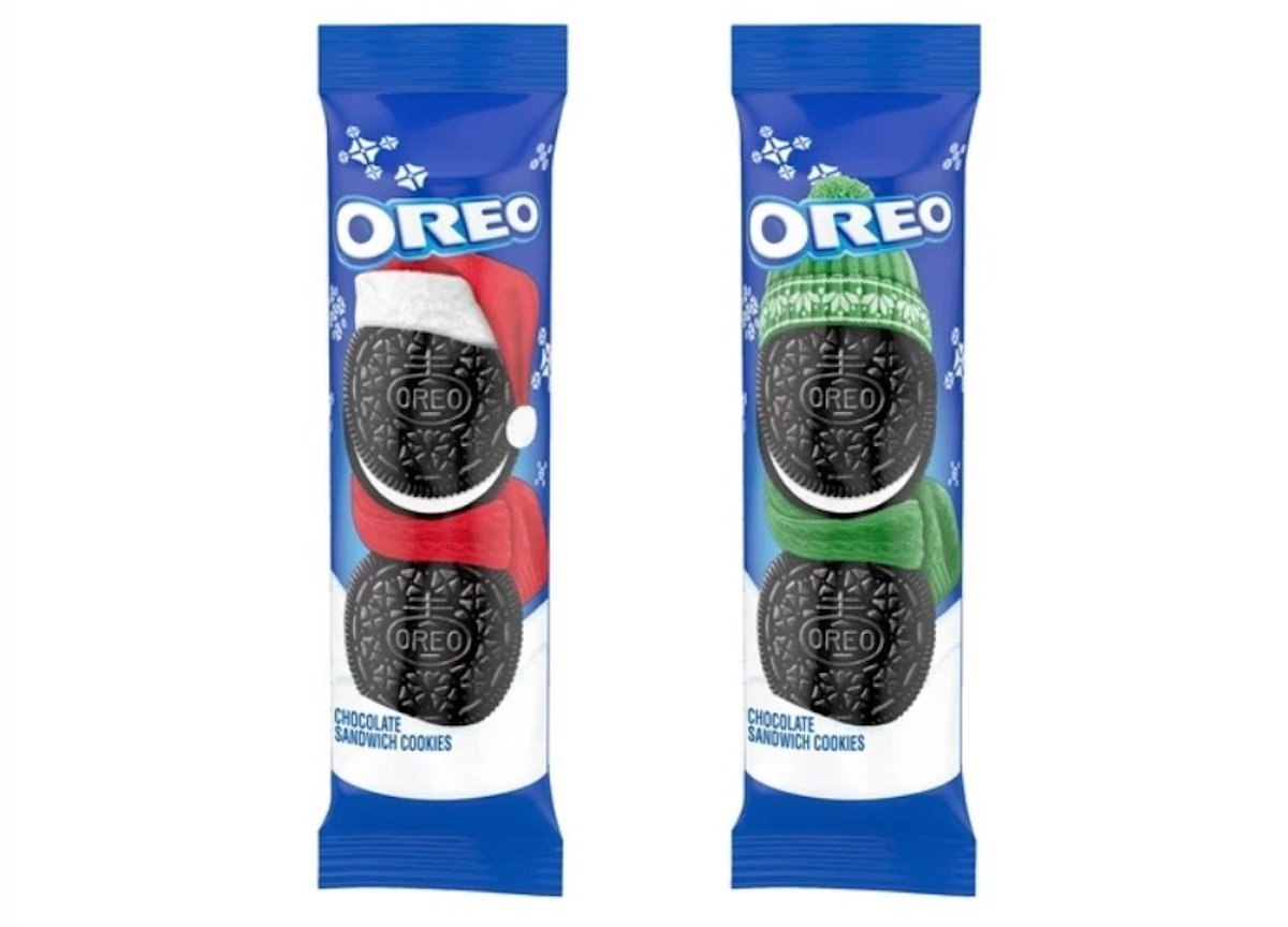 Two Oreo cookie packs with festive designs; one pack has an Oreo wearing a red Santa hat and scarf, the other has an Oreo with a green knit hat and scarf, both on a blue snowy background.