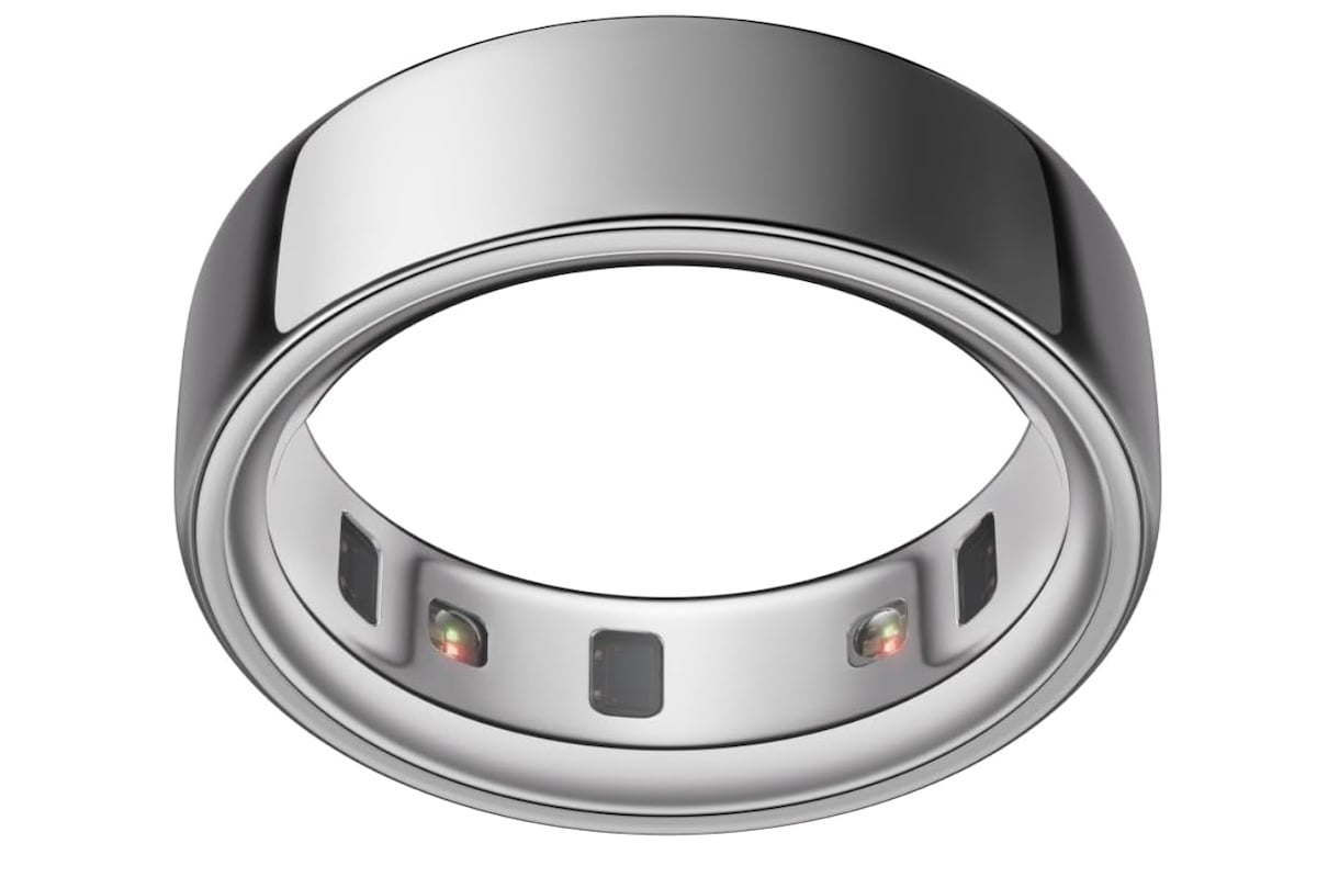 A silver smart ring is shown with sensors and tiny colored lights on its inner band, suggesting it is designed for tracking health or fitness data. The exterior is smooth and metallic.
