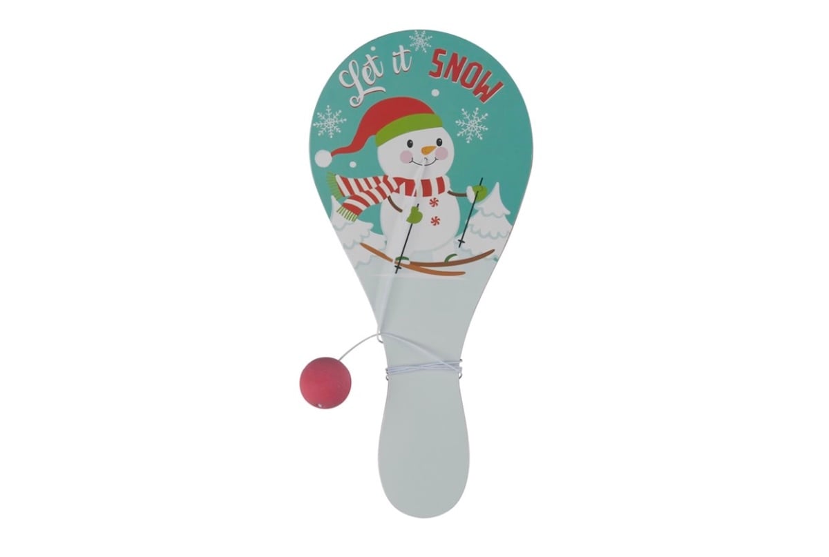 A paddle ball toy with a light blue background, featuring a smiling snowman in a red hat and scarf, two trees, snowflakes, and the words “Let it Snow.” A red ball is attached to the paddle with a string.